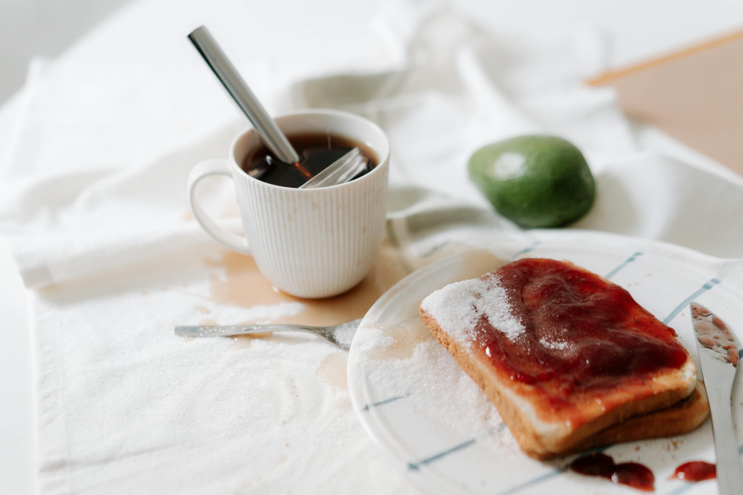 Przytulna, niechlujna scena śniadaniowa z kawą, rozsypanym cukrem i tostami z dżemem.