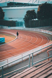 Sportowiec biegnący po bieżni na stadionie sportowym w Wiesbaden z pustymi trybunami.
