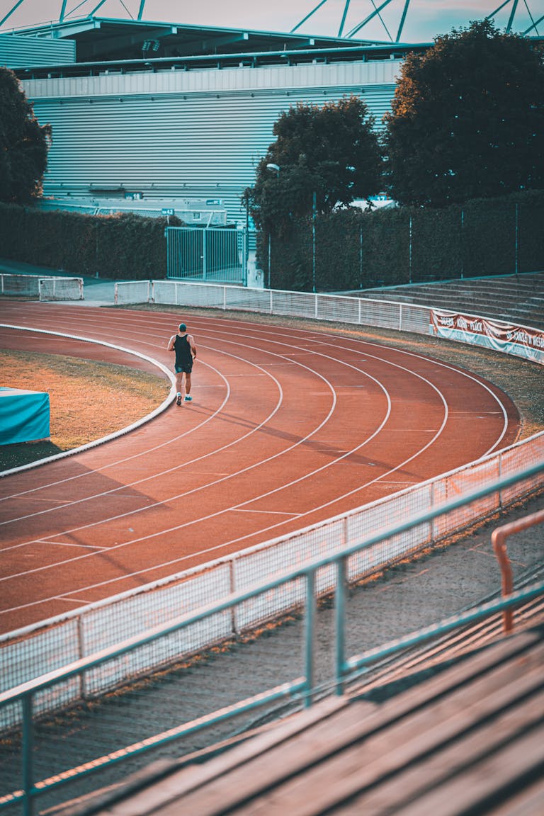 Sportowiec biegnący po bieżni na stadionie sportowym w Wiesbaden z pustymi trybunami.