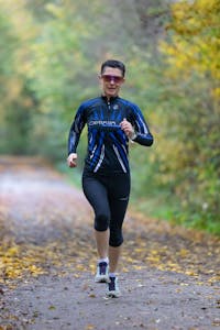 Woman in activewear jogging on a forest path in Frankfurt, capturing an outdoor fitness moment.