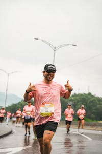 Biegacze w żywym maratonie, w różowych koszulkach, pokazujący entuzjazm i pracę zespołową.