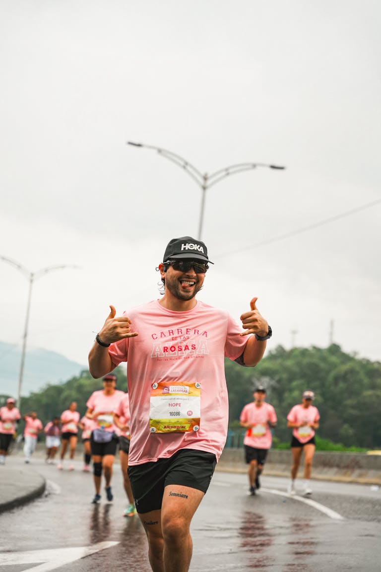 Biegacze w żywym maratonie, w różowych koszulkach, pokazujący entuzjazm i pracę zespołową.