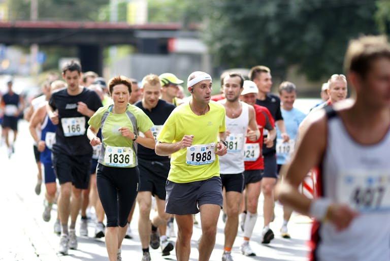 Zróżnicowana grupa biegaczy aktywnie uczestniczących w maratonie na ulicy miasta w ciągu dnia.