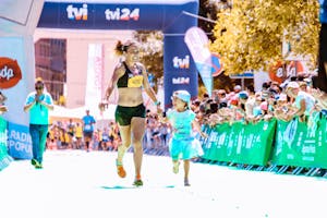 Radosna matka i córka przekraczają linię mety maratonu trzymając się za ręce, emanując szczęściem i energią.