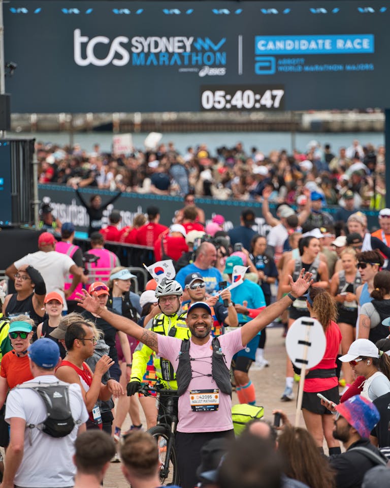 Radośni uczestnicy przekraczający linię mety podczas maratonu w Sydney, uchwyceni w emocjonującym momencie.