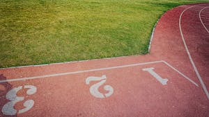 Widok z lotu ptaka na tętniącą życiem bieżnię na świeżym powietrzu i bujne, zielone boisko sportowe.