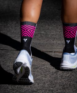 Zbliżenie na nogi sportowca w różowych skarpetkach i tenisówkach na chodniku na świeżym powietrzu.