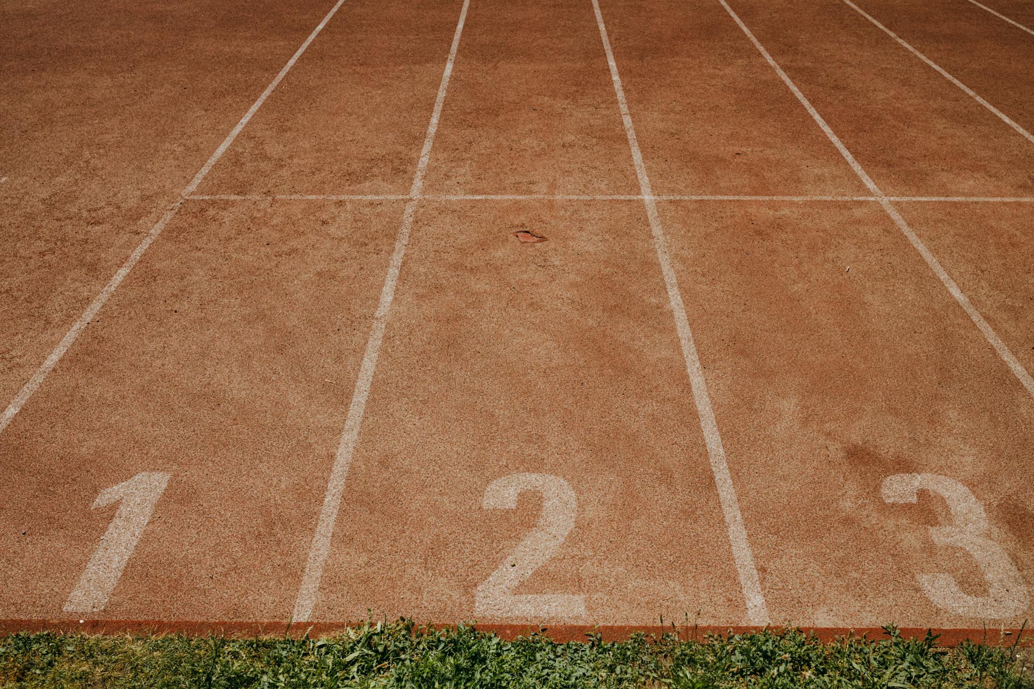 Zewnętrzna bieżnia sportowa z torami oznaczonymi numerami od 1 do 3, gotowa do organizacji zawodów lekkoatletycznych.